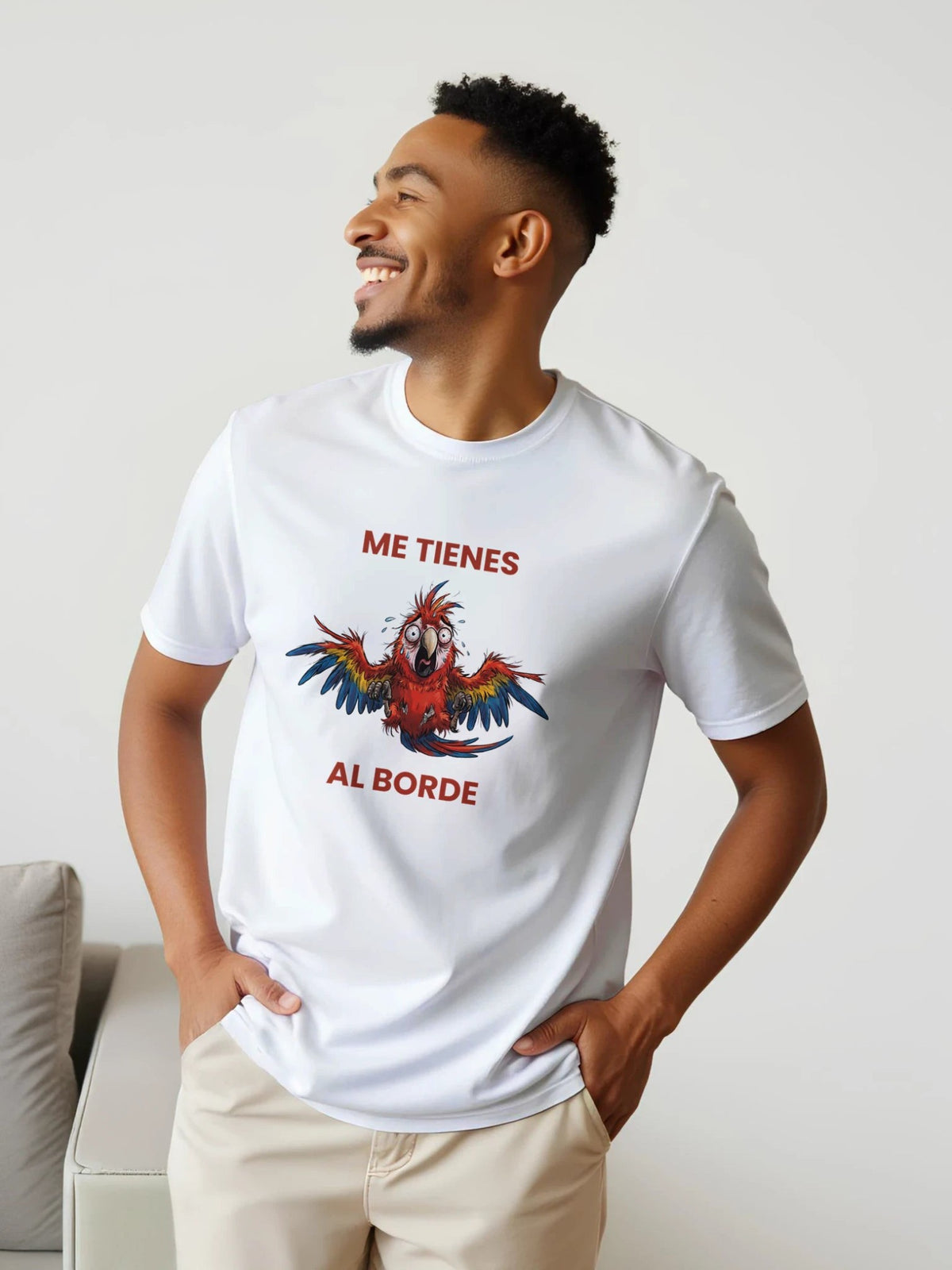 Hombre sonriente vistiendo camiseta blanca de algodón El Cachicamo con diseño de guacamaya y texto Al Borde