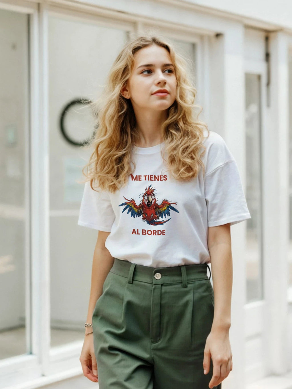 Mujer rubia con camiseta blanca de algodón El Cachicamo con estampado de guacamaya y texto Me tienes al borde